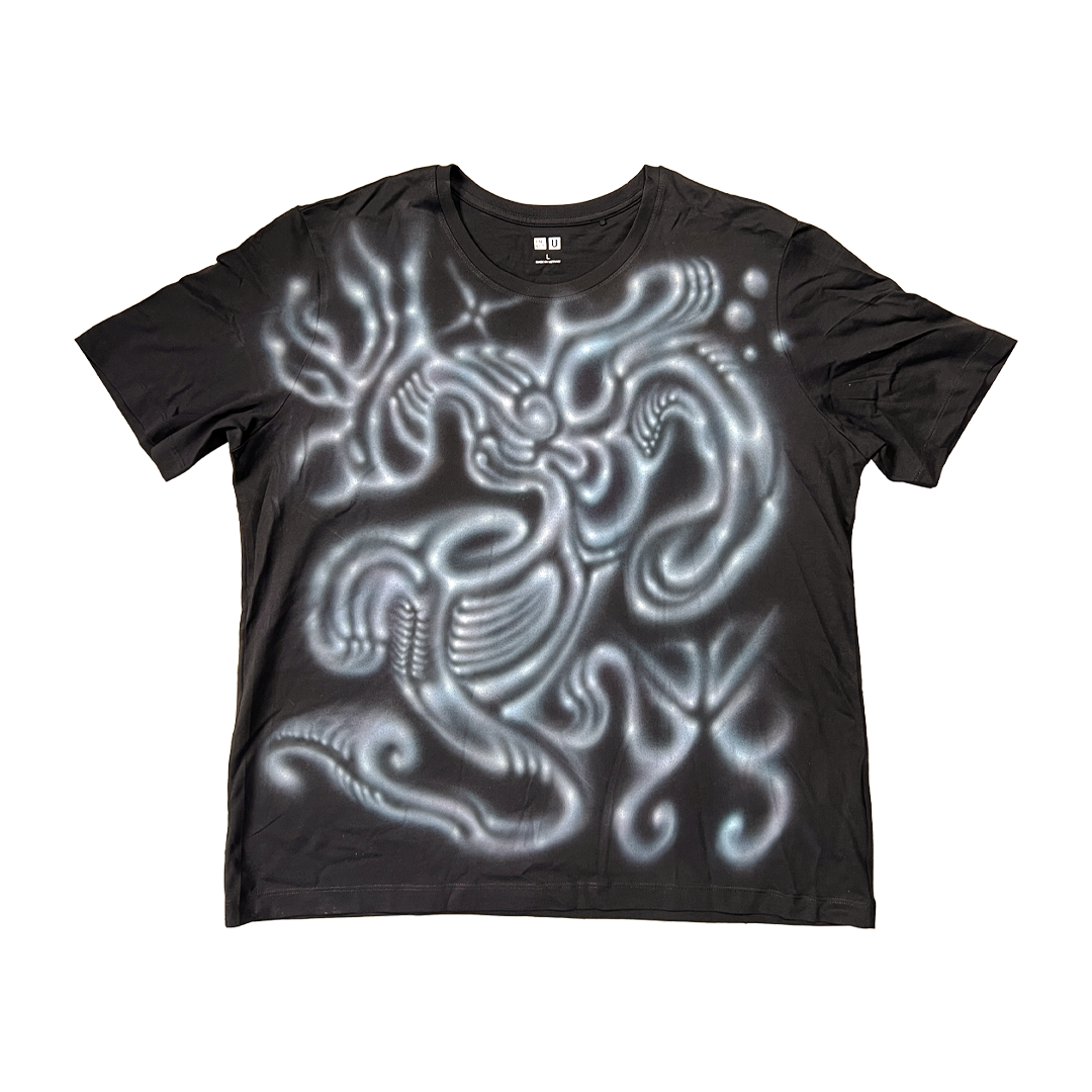 Black t-shirt with a glowing white alien design on a white background